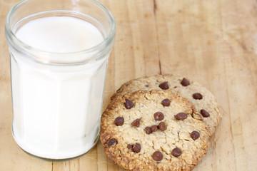 snack: glass of milk and chocolate chip cookies on wooden background

