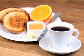 european breakfast: cup of coffee, toasts, jam, butter and orange on white plate
