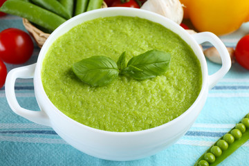 Tasty peas soup and vegetables on table close up