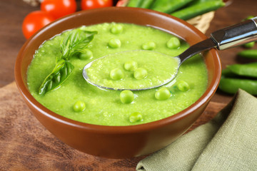 Tasty peas soup and cherry tomatoes on table close up
