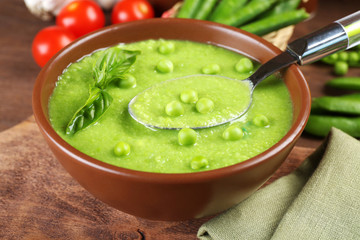 Tasty peas soup and cherry tomatoes on table close up