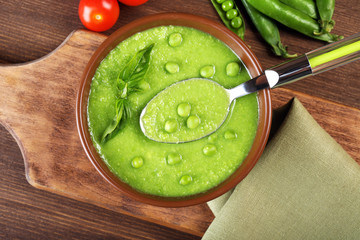 Tasty peas soup and cherry tomatoes on table close up