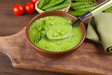 Tasty peas soup and cherry tomatoes on table close up