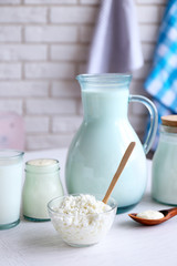 Dairy products on wooden table, on brick wall background