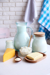Dairy products on wooden table, on brick wall background