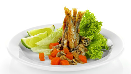 Fried small fish on plate with lettuce and lime isolated on white