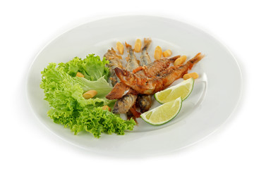 Fried small fish on plate with lettuce and lime isolated on white