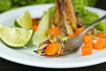 Fried small fish with carrot and greens on table close up