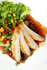 Slices of chicken fillet with sauce and vegetables on plate close up