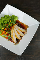 Slices of chicken fillet with sauce and vegetables on table close up