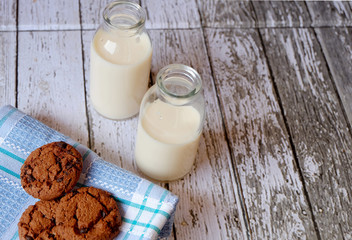 Horizontal shot of some chocolate cookies and two glasses of milk on a wooden table
