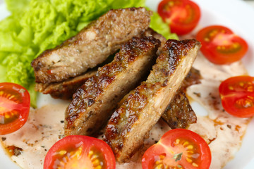 Tasty slices of meat with sauce and cherry tomato on plate close up