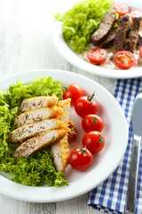 Slices of chicken fillet with spices and cherry tomato on table close up