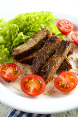 Tasty slices of meat with sauce and cherry tomato on plate close up