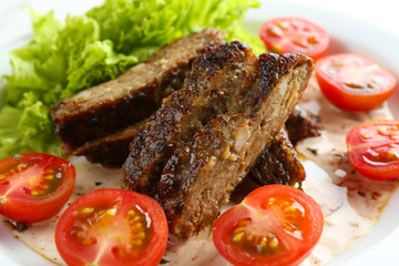 Tasty slices of meat with sauce and cherry tomato on plate close up