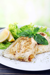 Dish of fish fillet with greens and lemon on bright background