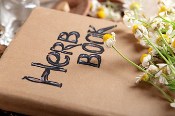 Old book with dry flowers on table close up