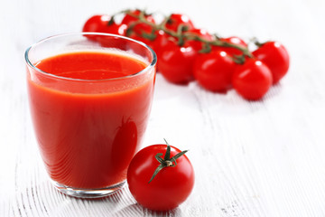 Glass of tomato juice on wooden background