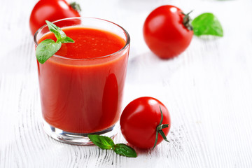 Glass of tomato juice on wooden background