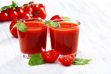 Glasses of tomato juice on wooden table, closeup
