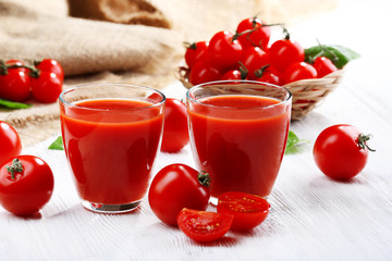 Glasses of tomato juice on wooden table, closeup
