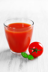 Glass of tomato juice on wooden background