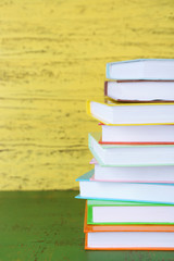 Stack of books on yellow wooden background