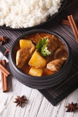 Thai massaman curry with chicken in a bowl and rice on the table. vertical
