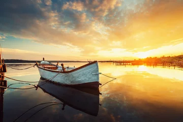 Fototapeten Sonnenuntergang über ruhigem See und Boot, Himmel reflektiert im Wasser © ValentinValkov