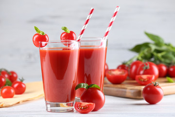 Glasses of tomato juice with vegetables on wooden table close up