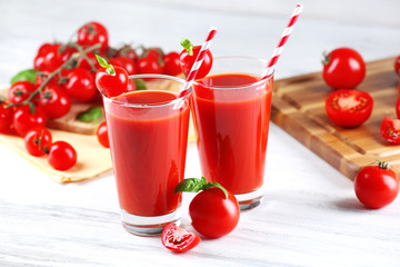 Glasses of tomato juice with vegetables on wooden table close up