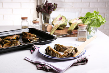 Roasted artichokes on plate, on kitchen table background