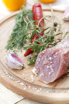 Raw pork tenderloin with spices on a wooden board, selective focus