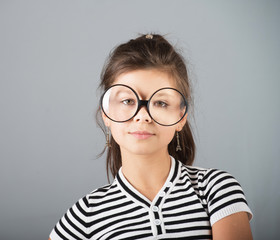 Portrait of a preteen girl in big glasses, studio shot, gray background