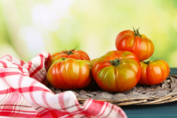 Green tomatoes in basket on bright background