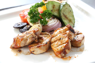 Grilled chicken with roasted vegetables on white dish. BBQ