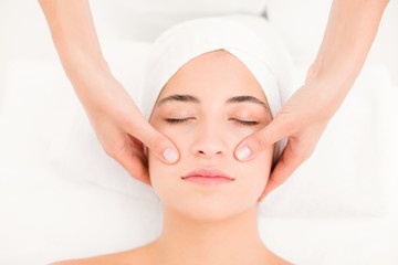 Fototapeta na wymiar Attractive young woman receiving facial massage at spa center