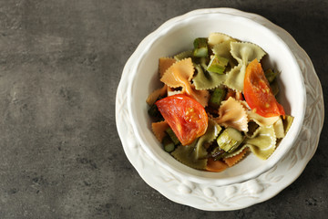 Roasted asparagus and tasty colorful pasta with vegetables in bowl on colorful background