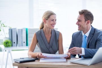 Happy colleagues working together on laptop and folder