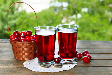 Glasses of sweet homemade cherry compote on table on bright background