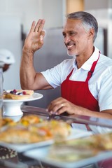 Happy barista gesturing ok sign behind counter