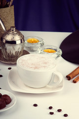 Coffee cup, coffee beans, chocolate candies and candles on a white table