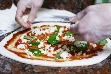 Chef preparing pizza on marble table, closeup