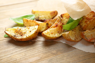 Baked potatoes in parchment on wooden table, closeup