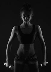 Fototapeta na wymiar sporty girl doing exercise with dumbbells bw studio shot