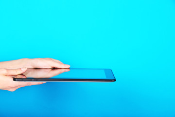 Female hands using tablet on blue background
