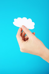 Hand holding paper cloud on blue background. Cloud computing concept.