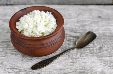 Crumbly homemade cottage cheese in a clay pot