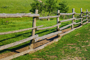 Fototapeta na wymiar old rural wooden fence on green grass backgrounds