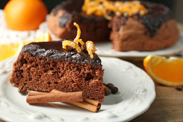 Cake with Chocolate Glaze and orange on plate, on wooden table, on dark  background